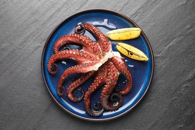 Photo of Fried octopus with herb sauce and lemon on grey textured table, top view