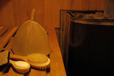 Photo of Bath accessories and felt wool hat on bench in sauna. Space for text