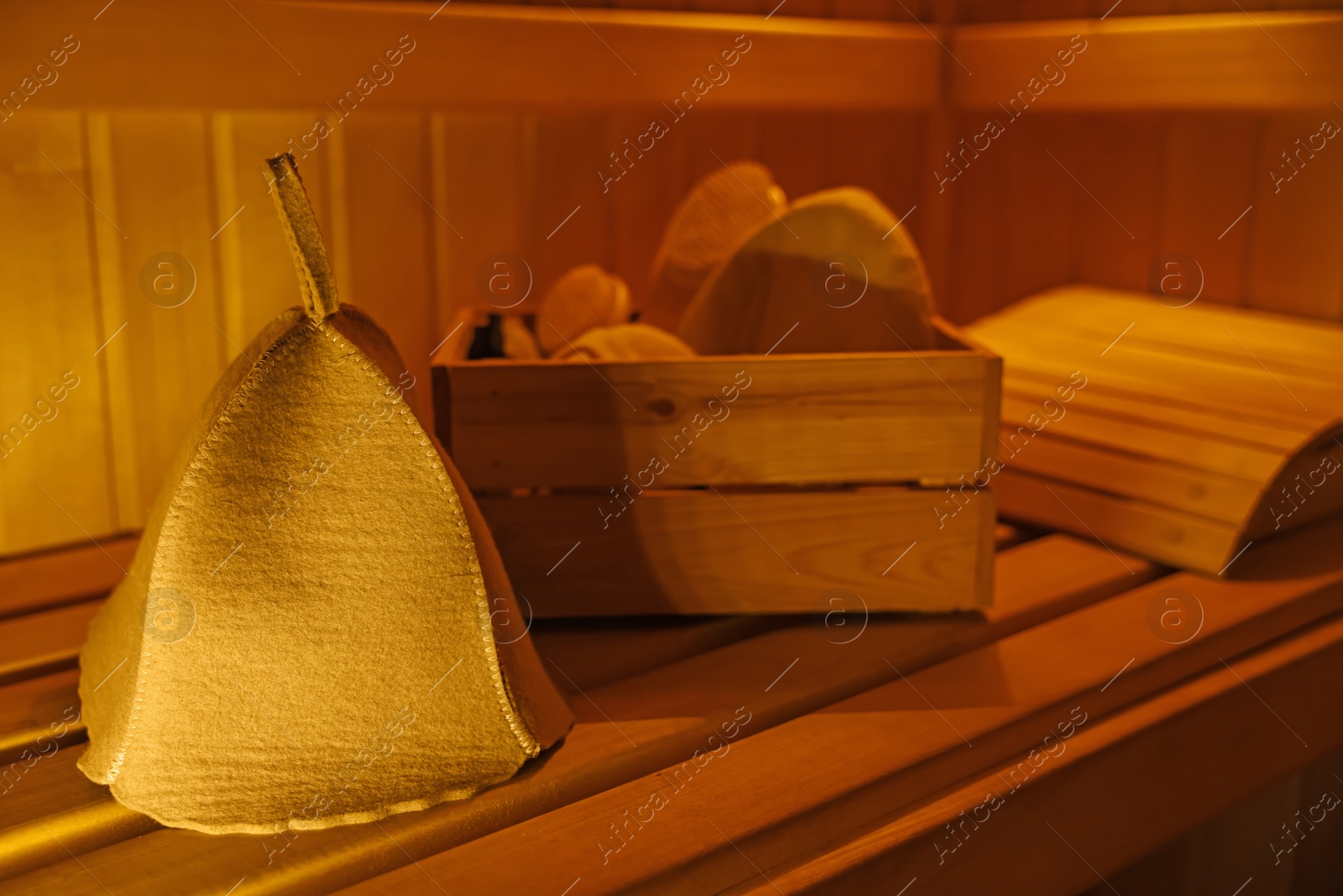 Photo of Crate with bath accessories and felt wool hat on bench in sauna