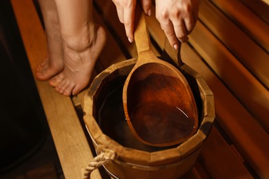 Photo of Woman with bucket of water in sauna, closeup