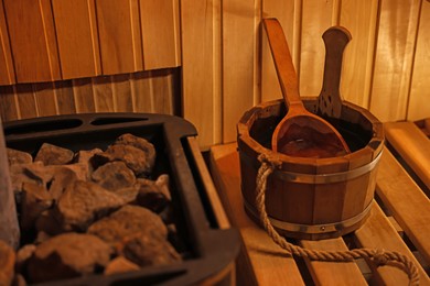 Photo of Bucket with ladle near stove in sauna