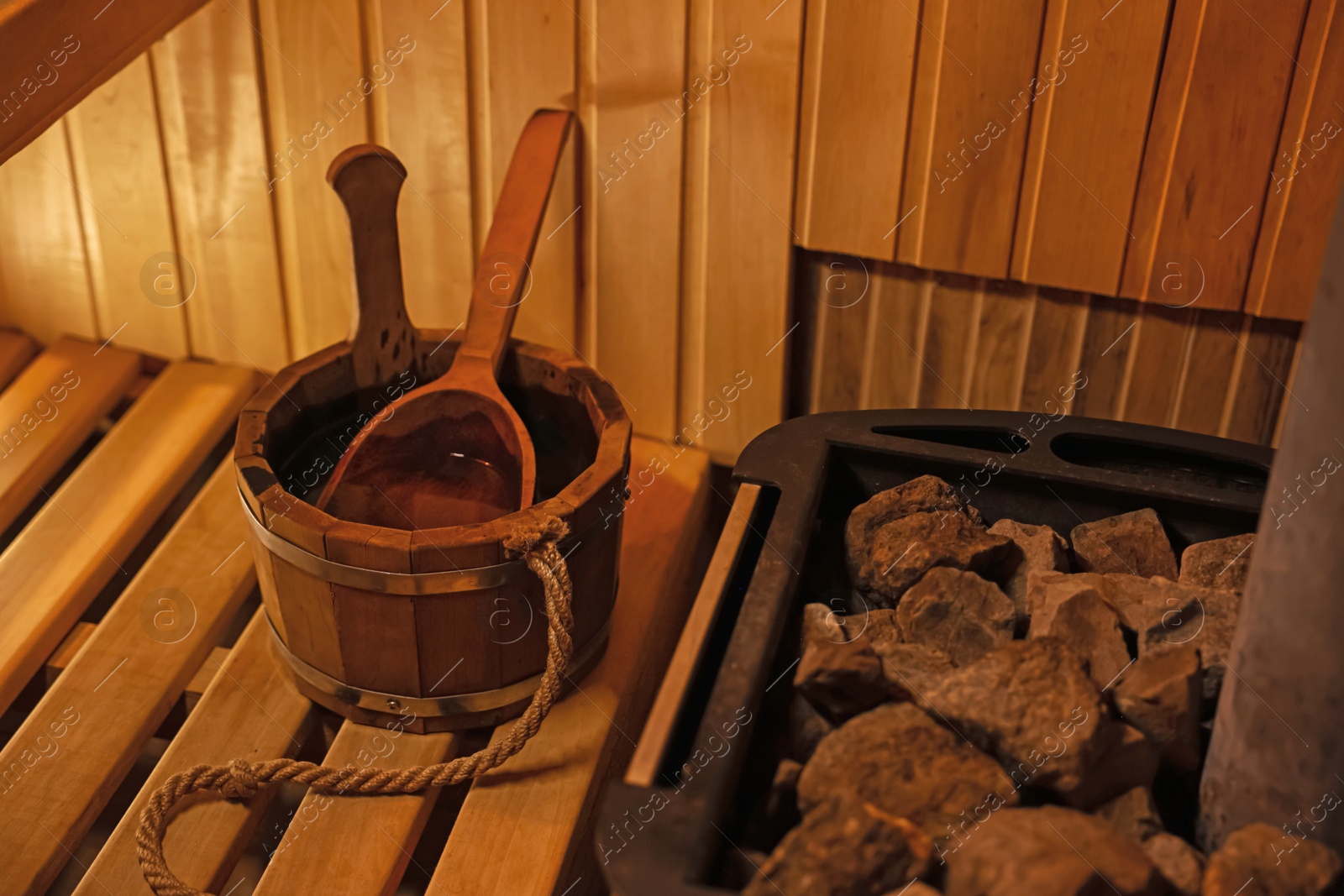 Photo of Bucket with ladle near stove in sauna