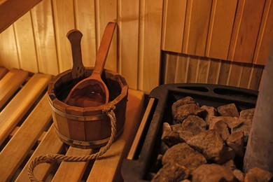 Photo of Bucket with ladle near stove in sauna