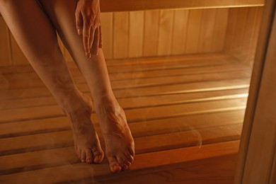 Photo of Young woman relaxing in hot sauna, closeup. Space for text