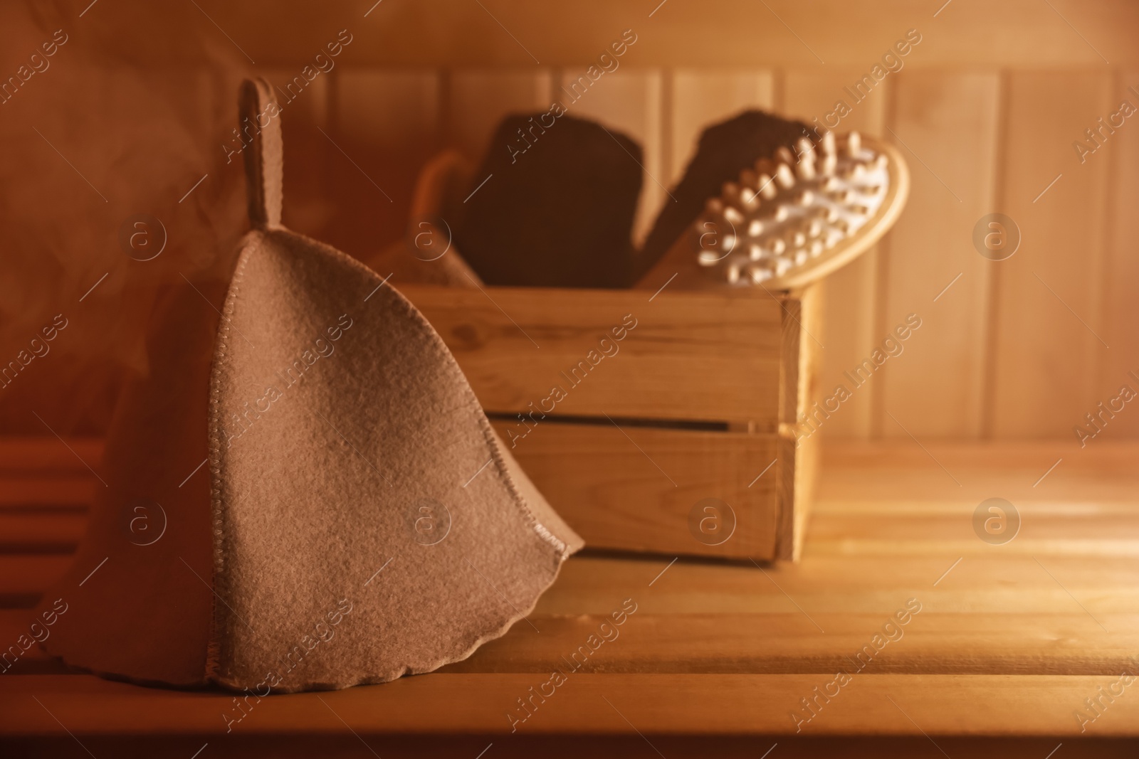 Photo of Crate with bath accessories and felt wool hat on wooden bench in sauna