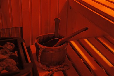 Photo of Bucket with ladle on wooden bench in sauna