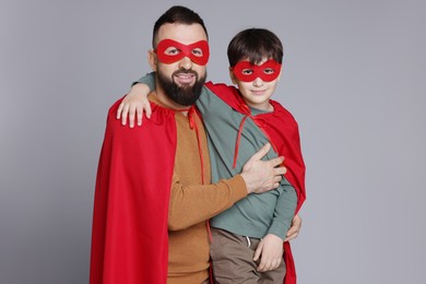 Photo of Father and his son wearing superhero costumes on gray background