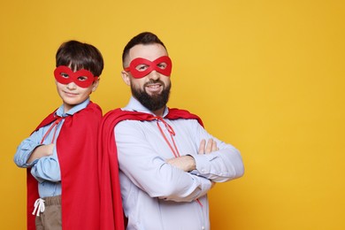 Photo of Father and his son wearing superhero costumes on orange background, space for text