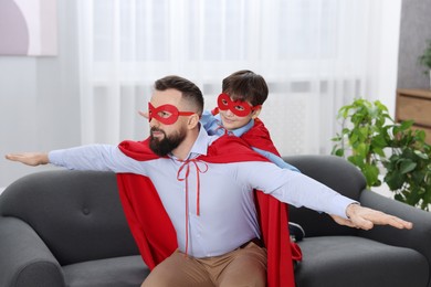 Photo of Father and his son wearing superhero costumes at home