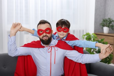 Father and his son wearing superhero costumes at home