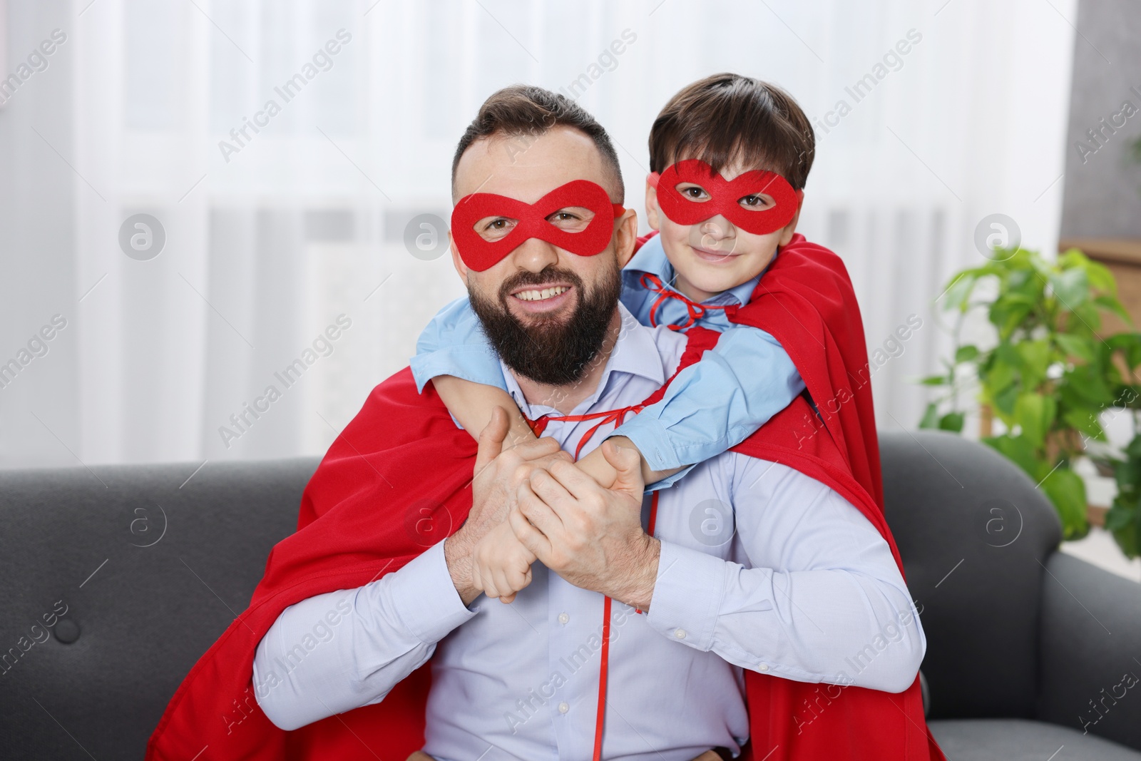 Photo of Father and his son wearing superhero costumes at home