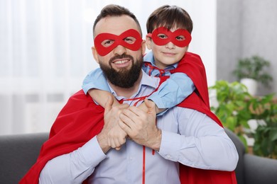 Photo of Father and his son wearing superhero costumes at home