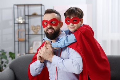 Photo of Father and his son wearing superhero costumes at home