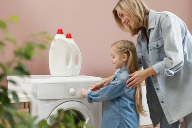 Little girl and her mom doing laundry together at home