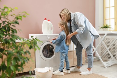 Little girl and her mom doing laundry together at home