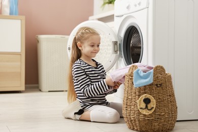 Photo of Cute little girl doing laundry at home