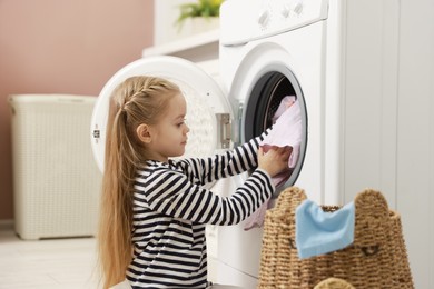 Photo of Cute little girl doing laundry at home