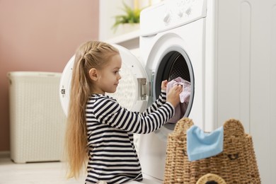 Photo of Cute little girl doing laundry at home