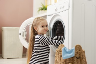 Photo of Cute little girl doing laundry at home