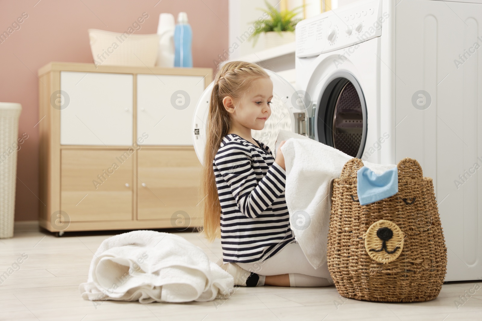 Photo of Cute little girl doing laundry at home