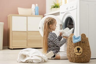 Photo of Cute little girl doing laundry at home