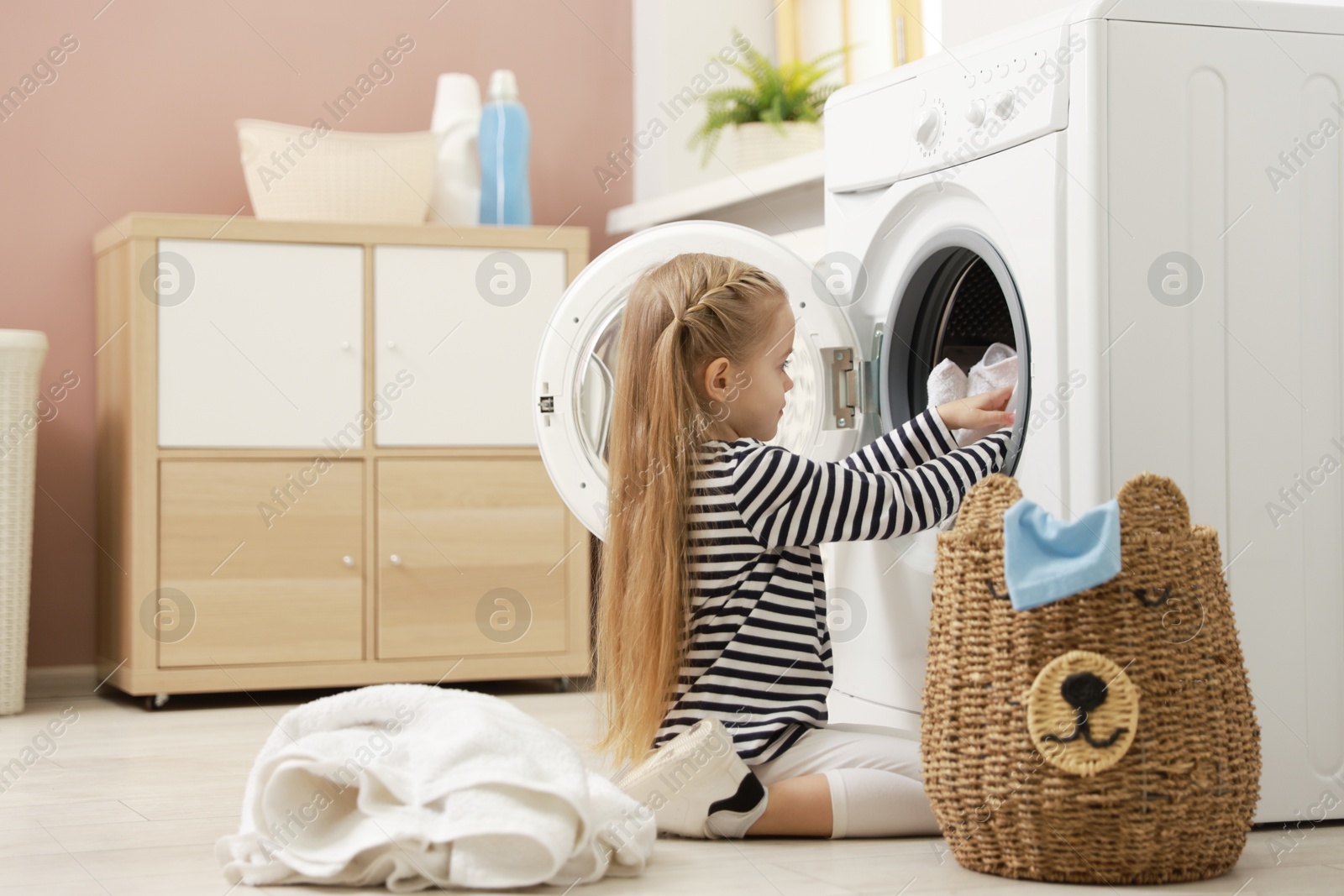 Photo of Cute little girl doing laundry at home