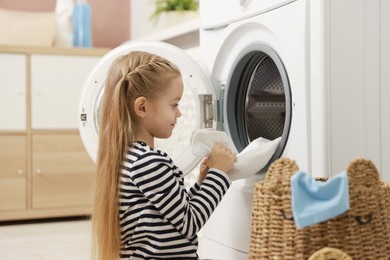 Cute little girl doing laundry at home