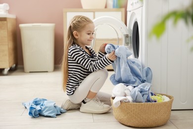 Photo of Cute little girl doing laundry at home