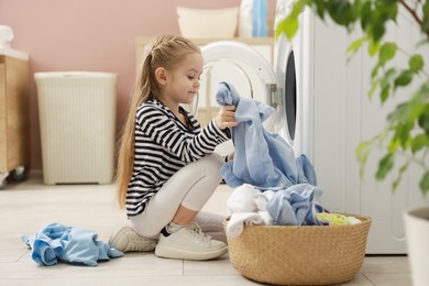 Photo of Cute little girl doing laundry at home