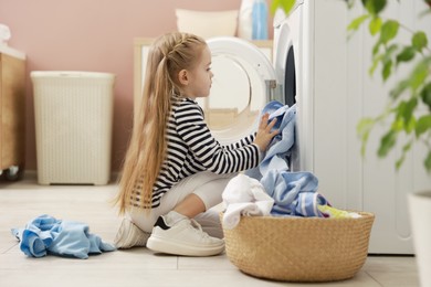 Photo of Cute little girl doing laundry at home