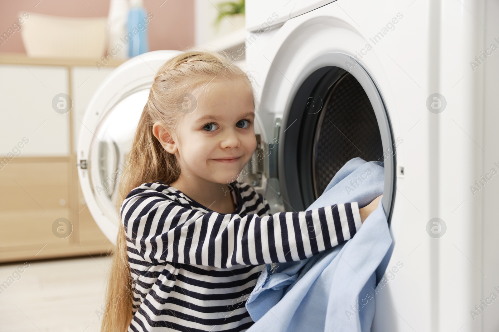 Photo of Cute little girl doing laundry at home