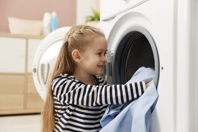 Photo of Cute little girl doing laundry at home