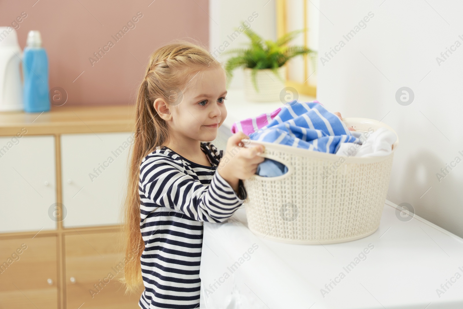 Photo of Cute little girl doing laundry at home