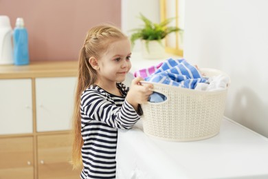 Photo of Cute little girl doing laundry at home