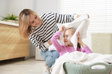 Photo of Mother and daughter having fun while doing laundry together at home