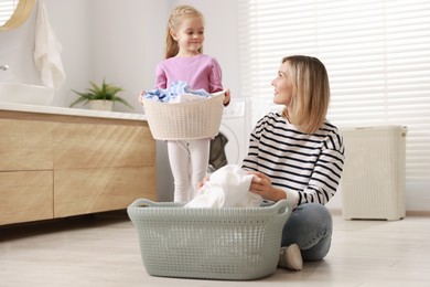 Little girl and her mom doing laundry together at home