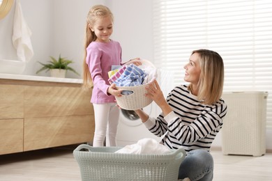 Little girl and her mom doing laundry together at home