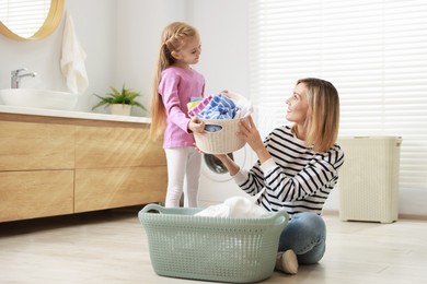 Little girl and her mom doing laundry together at home