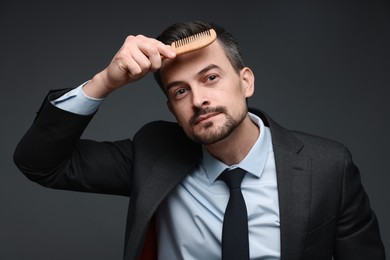 Photo of Handsome businessman combing his hair on dark background