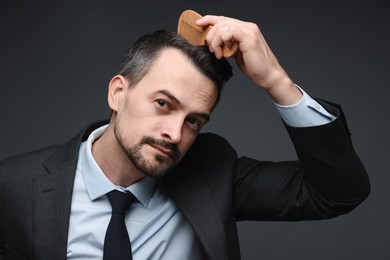 Photo of Handsome businessman combing his hair on dark background