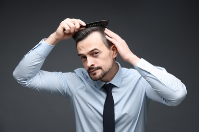 Photo of Handsome man combing his hair on dark background