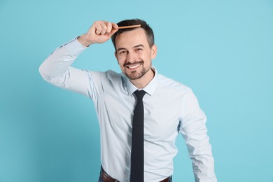 Photo of Handsome man stylish his hair with comb on light blue background