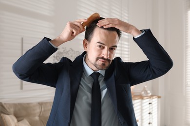 Photo of Handsome man combing his hair at home