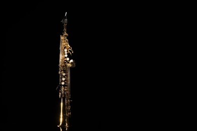 Photo of Jazz. One saxophone on mirror surface against black background, space for text