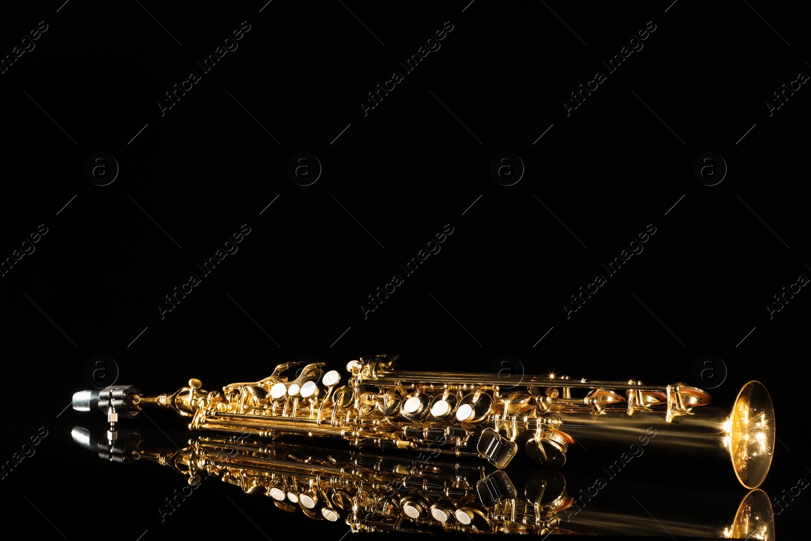 Photo of Jazz. One saxophone on mirror surface against black background, space for text