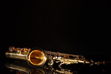 Photo of Jazz. One saxophone on mirror surface against black background, space for text