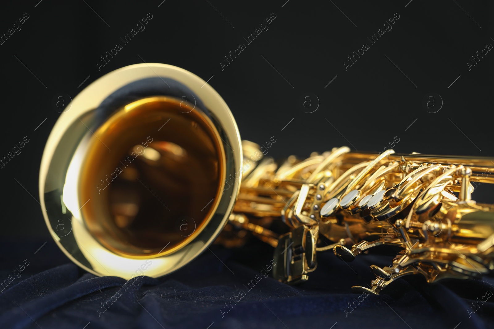 Photo of Jazz. One beautiful saxophone on dark blue fabric, closeup