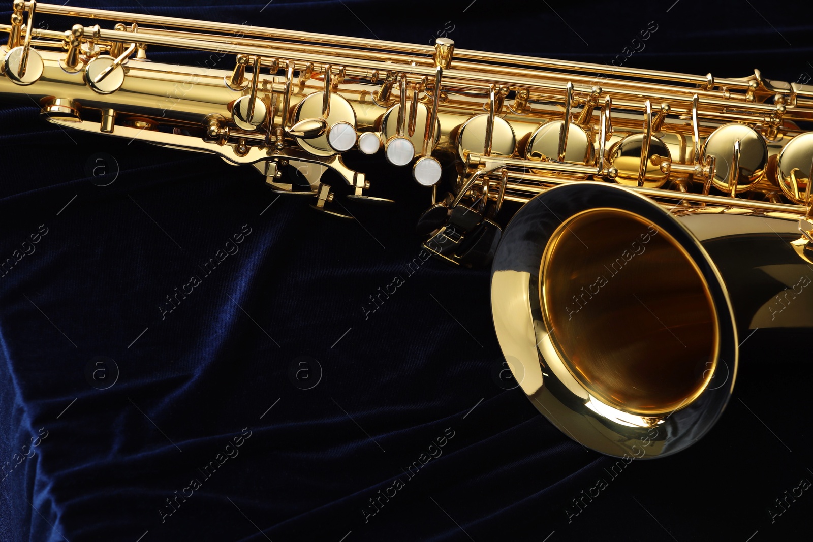 Photo of Jazz. One beautiful saxophone on dark blue fabric, closeup. Space for text