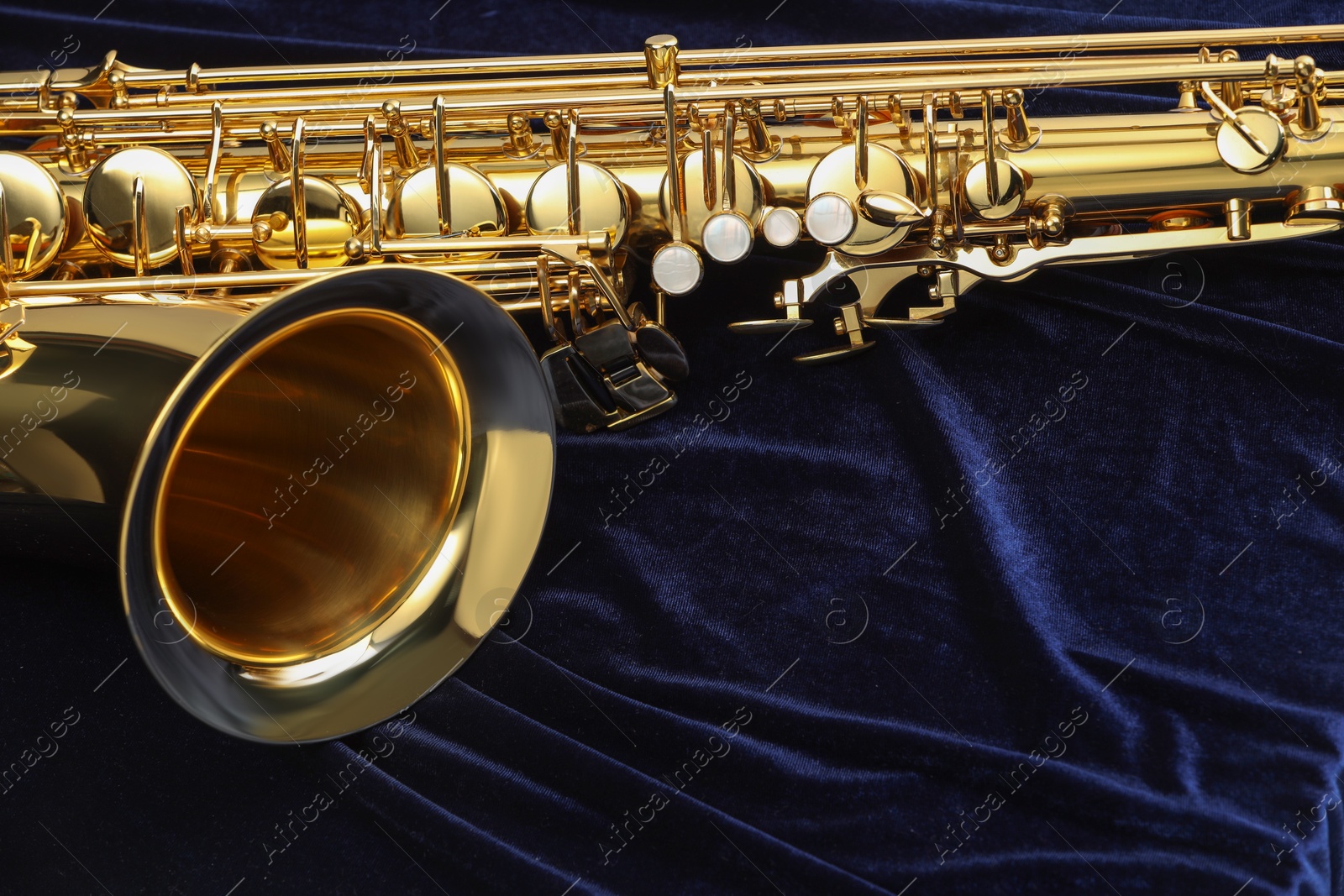 Photo of Jazz. One beautiful saxophone on dark blue fabric, closeup. Space for text