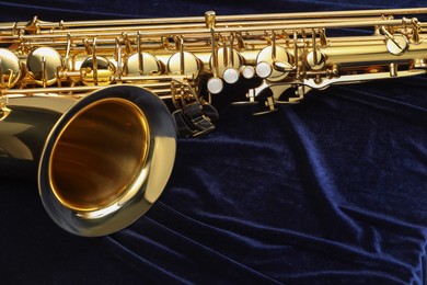 Photo of Jazz. One beautiful saxophone on dark blue fabric, closeup. Space for text